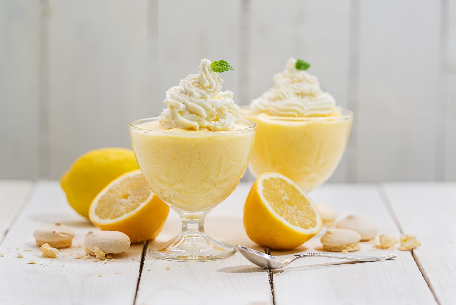 Foto di un dolce al cucchiaio a base di uova con dei limoni tagliati a metà.